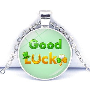 Détail macro du pendentif Good Luck avec fer à cheval, trèfle et patch en verre poli