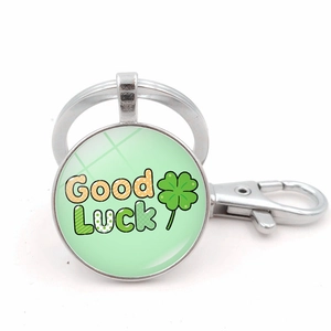 Detail of a silver circular keychain with a green four-leaf clover and Good Luck text