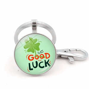Close-up of a silver keychain with a green four-leaf clover and Good Luck text