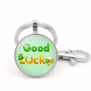 Detailed macro of a silver Good Luck keychain with green clover and horseshoe graphics