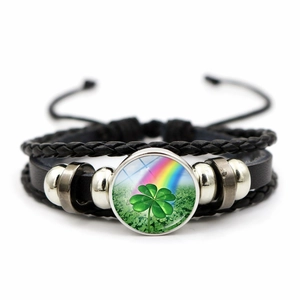 Detail of multi-layer leather bracelet with green four-leaf clover glass charm on white background