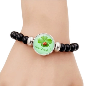 Bracciale portafortuna con perle nere e ciondolo a quadrifoglio verde su fondo bianco