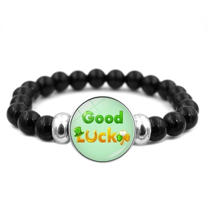 Dettaglio del bracciale di perline nere con quadrifoglio e scritta Good Luck