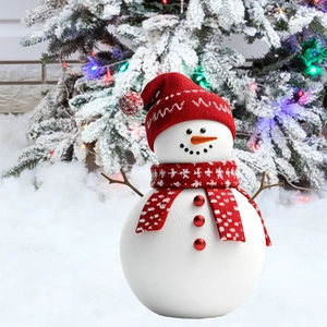 Detail view of a Christmas snowman lawn ornament with red scarf and hat in a snowy garden