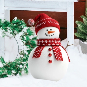 Close-up of a snowman garden stake with a red knitted hat and scarf in snowy garden