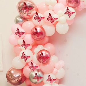 Detail van rode holle 3D vlinderstickers op een roze en gouden ballonboog
