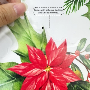 Détail montrant une main décollant un sticker mural de fleurs de Noël auto-adhésif