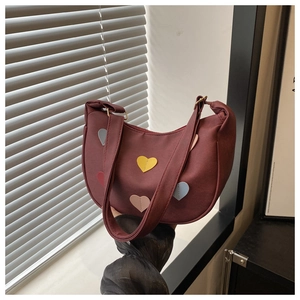 Detail of burgundy crescent bag with colorful leather heart patches and smooth zipper