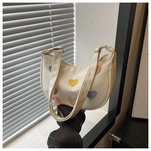Detail of white PU leather crescent bag with colorful heart patches and dual straps