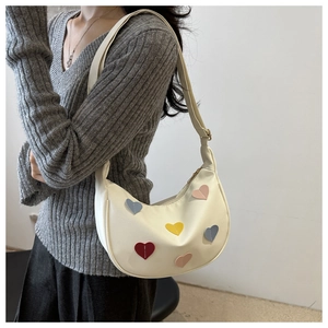 Détail du sac croissant crème avec écussons cœurs colorés et bandoulière réglable