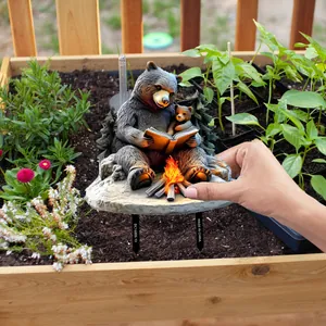 Détail de tuteur de jardin avec ours lisant au coin du feu et piquets de fixation