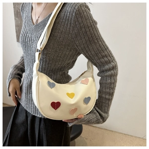 Détail du sac croissant beige avec des patchs de cœur colorés en cuir texturé