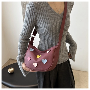 Détail du sac bandoulière bordeaux en forme de cœur avec large sangle en toile réglable