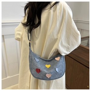 Détail du sac demi-lune en feutre gris avec patchs cœurs colorés et bandoulière réglable
