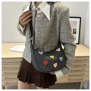 Detail of dark grey hobo bag with colorful heart patches and adjustable shoulder strap