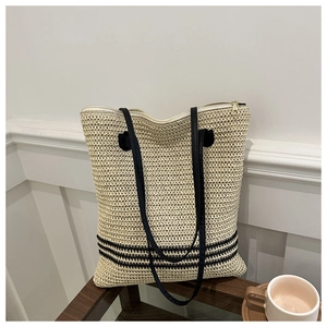 Detail of woven straw bucket bag with black stripes and secure zipper closure