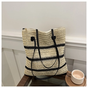 Close-up of beige woven straw tote bag with black stripes and leather handles