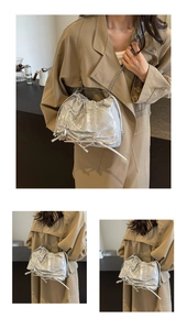 Detail of silver pleated tote bag with chain strap shown on khaki trench coat