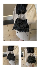 Detail showing black pleated texture and silver metal chain strap of the drawstring bag