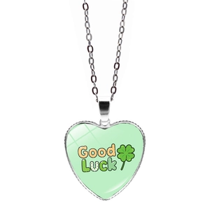 Detailed view of a silver heart pendant with green clover and Good Luck text