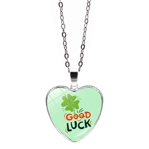 Detail of silver heart pendant with green four-leaf clover and Good Luck text