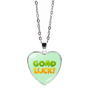 Macro view of heart-shaped Good Luck pendant with green clover and horseshoe details