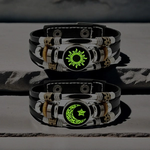 Luminous leather couple bracelets with sun and moon designs on stone background