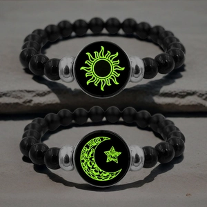 Leuchtende Sonnen- und Mond-Perlenarmbänder für Paare auf dunklem strukturiertem Stein