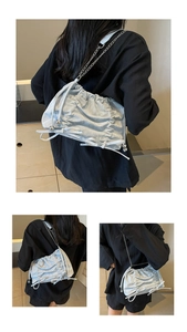Detail view of light blue pleated tote bag featuring chain strap and bow pendant
