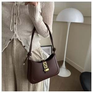 Detail of dark brown retro crescent bag featuring a gold geometric metal buckle clasp