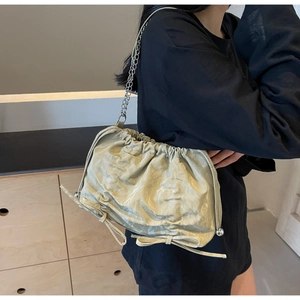 Detail view of light green pleated bucket bag with metal chain strap and bow decoration