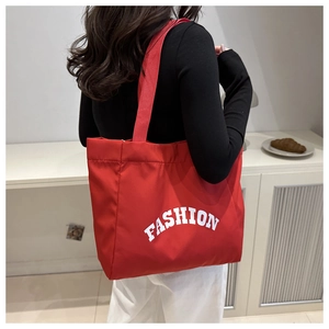 Vue détaillée du sac cabas rouge en toile avec inscription FASHION blanche et poignées