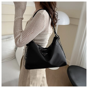 Detailed view of black nylon hobo bag with triangle metal logo and silver chain strap