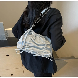 Detail of light blue pleated bucket bag featuring chain strap and bow decoration
