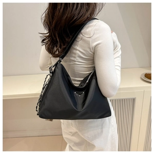 Rear view of model wearing a large black nylon tote bag with silver chain and metal logo