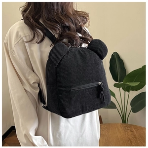 Détail du sac à dos en velours côtelé noir avec oreilles d'ours et tirettes tissées