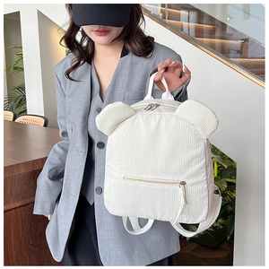 Gros plan du sac à dos en velours côtelé blanc avec oreilles d'ours et zip doré brillant