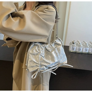 Detail of silver pleated bucket bag featuring metallic chain strap and drawstring design
