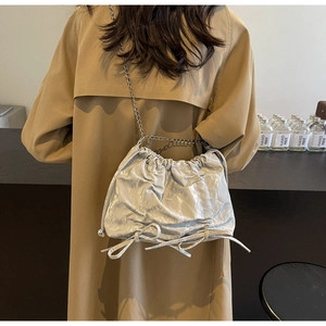 Detail of silver pleated bucket bag with metallic texture and drawstring bow accent