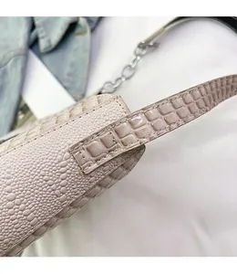 Close-up of beige crocodile pattern handbag with reinforced stitching and silver chain detail