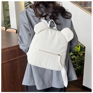 Détail d'un sac à dos en velours côtelé beige avec oreilles d'ours porté par un modèle