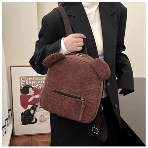 Détail d'un sac à dos en velours côtelé marron avec oreilles d'ours porté par un modèle