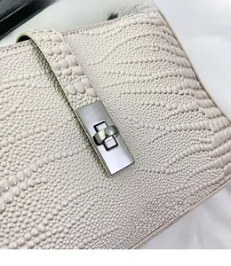 Close-up of the silver metal twist lock and textured cream leather of the stylish bag