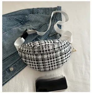 Detail of checkered canvas chest bag with white strap and triangle zipper puller