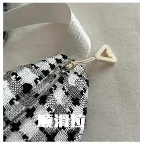 Detailed close-up of smooth metal zipper and black and white houndstooth tweed fabric