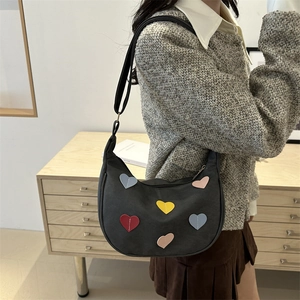Sac hobo en toile gris foncé avec patchs cœurs colorés et bandoulière sur un mannequin