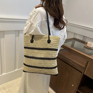 Minimalist straw tote bag with black stripes and leather straps for summer beach travel