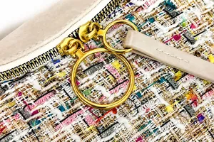 Macro detail of multicolored tweed fabric with gold circular zipper on saddle bag
