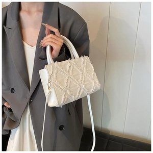 Detail of cream quilted crossbody bag featuring fringe texture and gold metal hardware