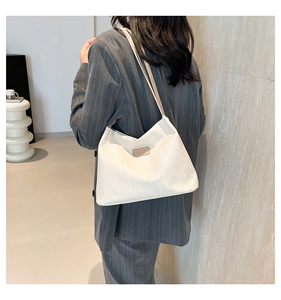 Detail of white woven canvas tote bag with a leather label and slim beige shoulder straps